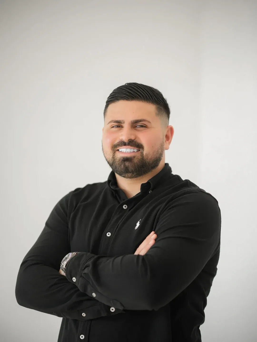 Porträt von Ugur Kosar im schwarzen Hemd, mit verschränkten Armen.